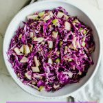 An overhead shot of red cabbage apple slaw in a white bowl.