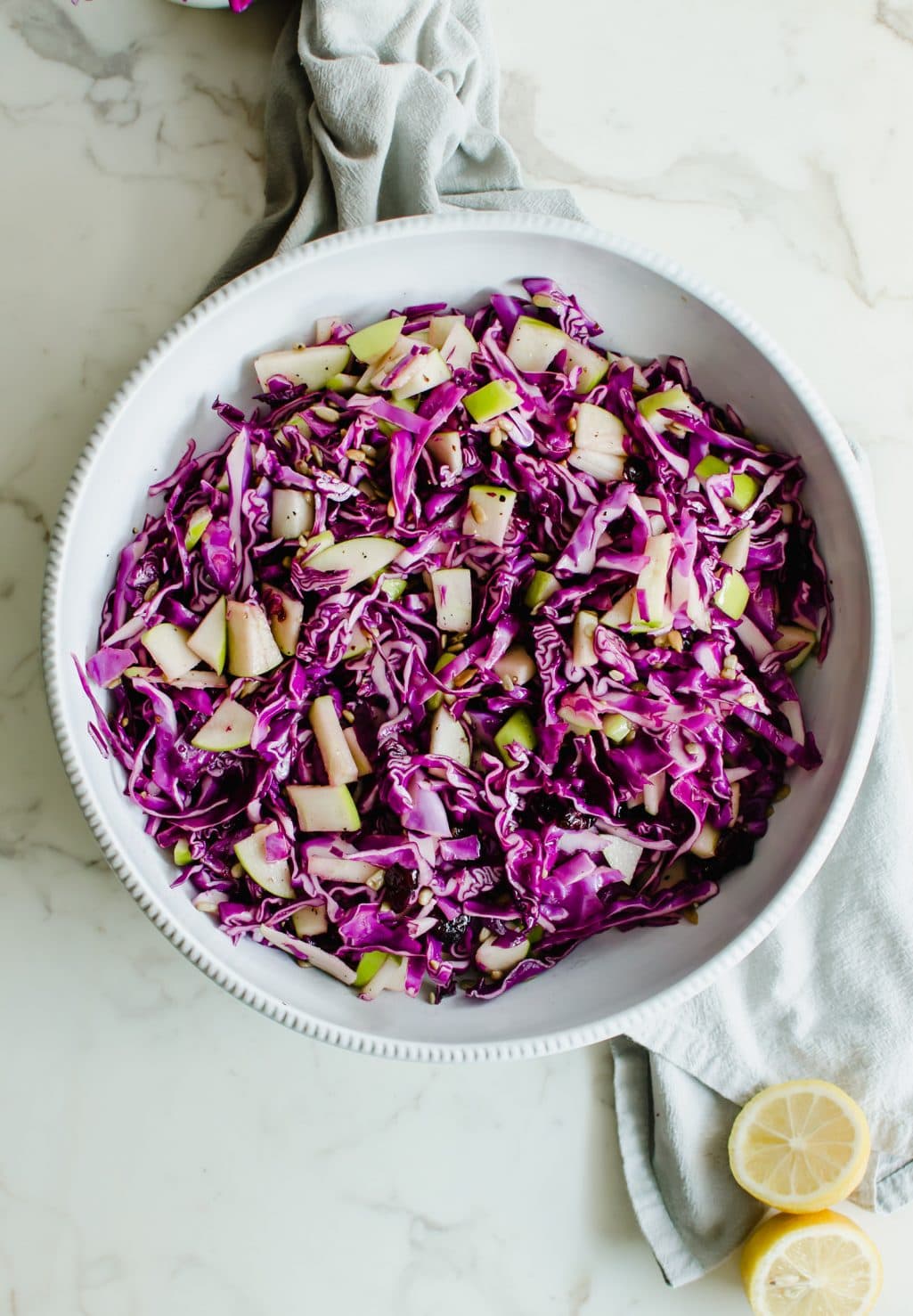 An overhead shot of a white bowl filled with red cabbage apple slaw.