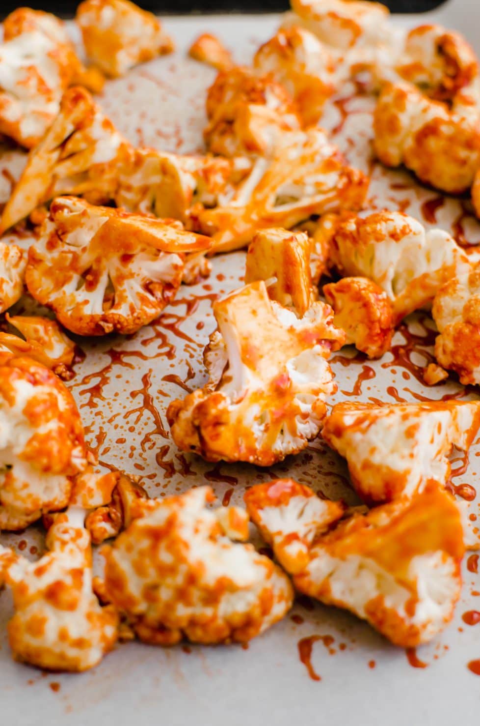 A close-up shot of cauliflower florets on a baking sheet coated in Korean-style sauce.