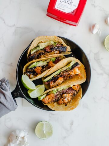 An overhead shot of a cast iron skillet filled with Korean-style beef tacos with roasted cauliflower.