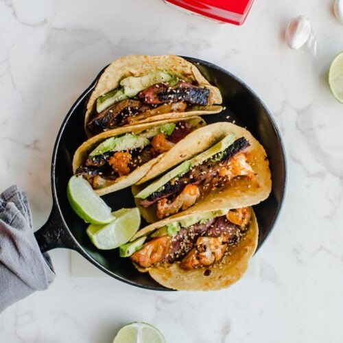 An overhead shot of a cast iron skillet filled with Korean-style beef tacos with roasted cauliflower.