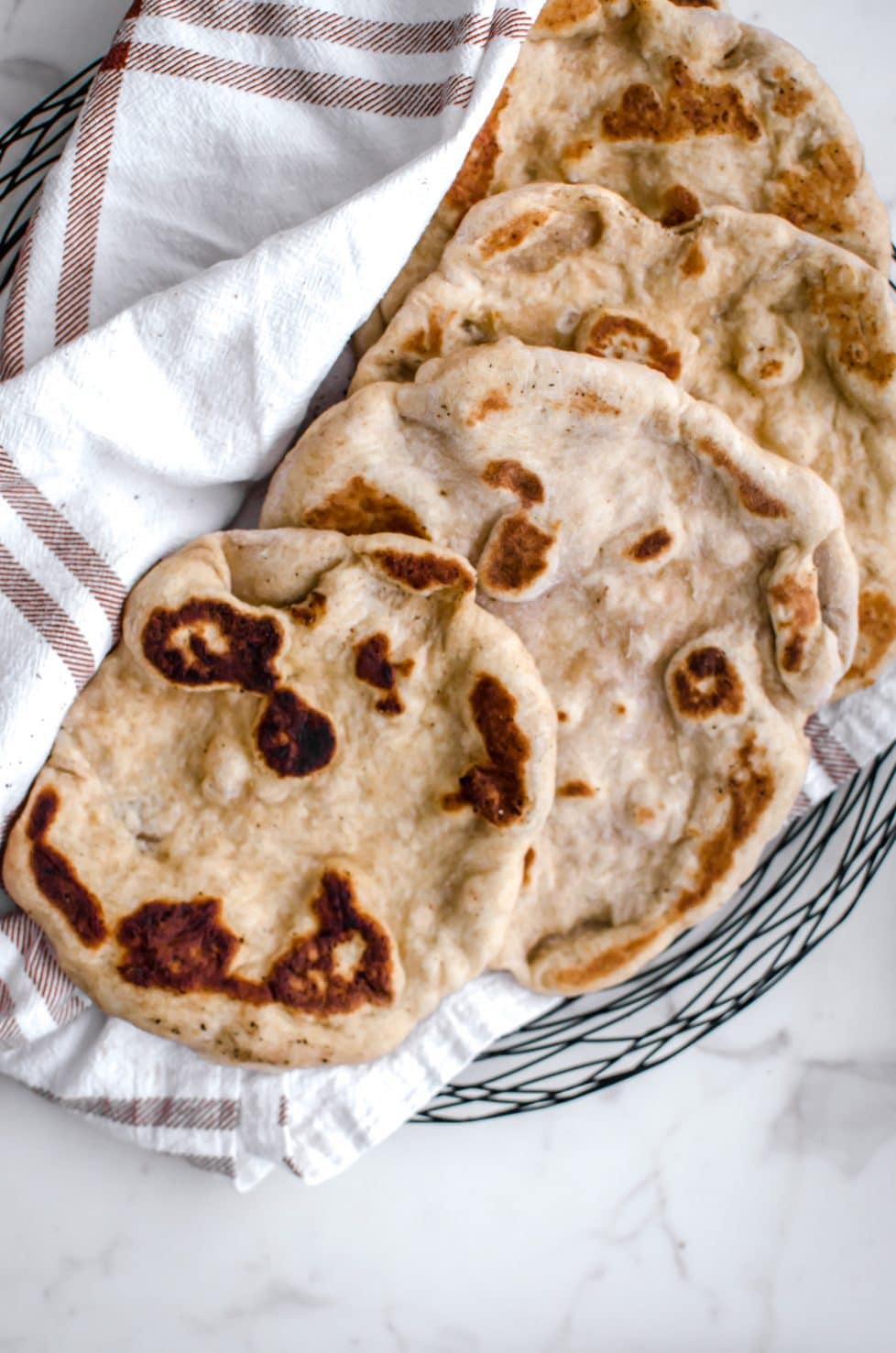 An overhead shot of a plate with pieces of naan and a plaid towel. 