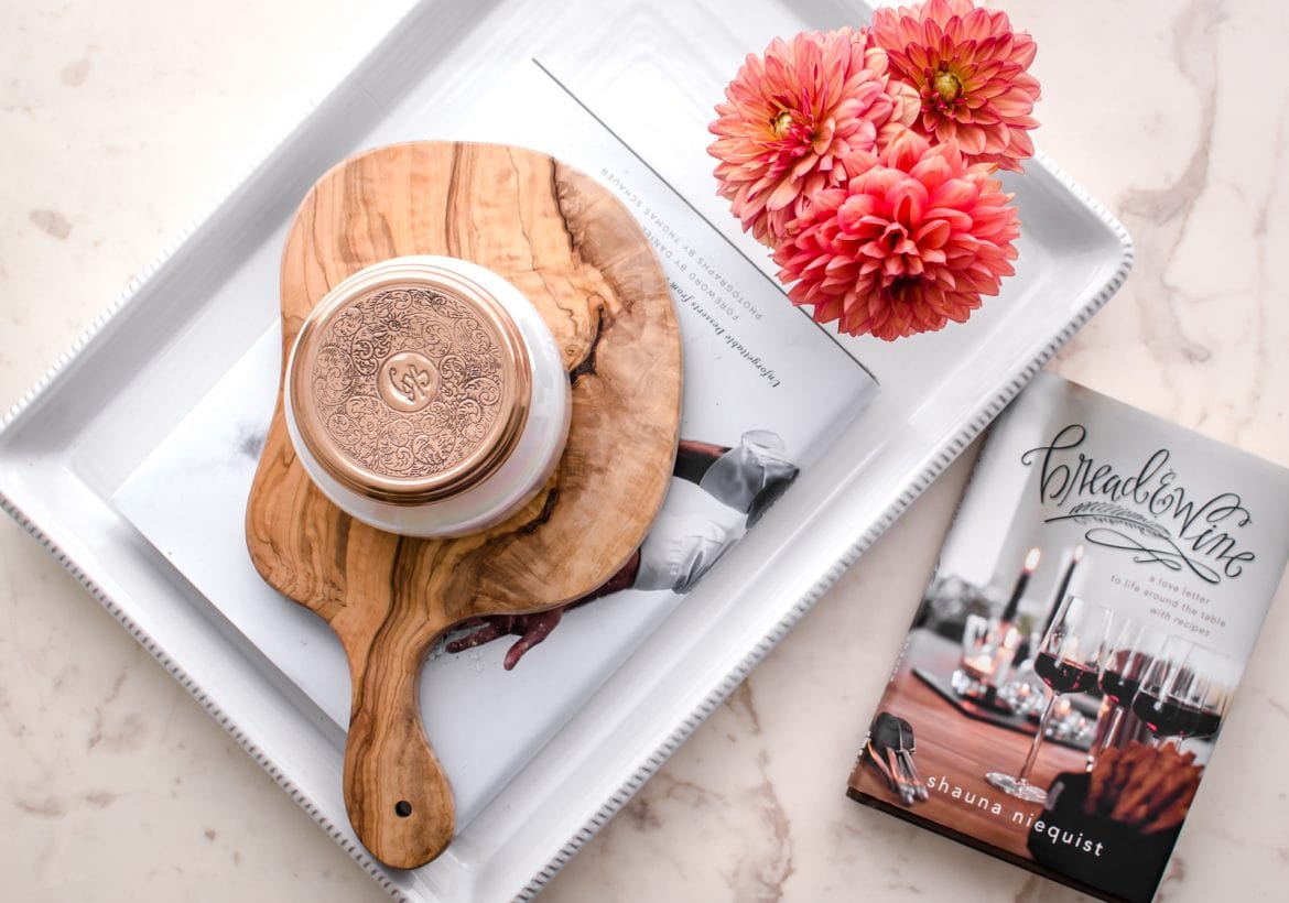 An overhead shot of the Bread and Wine book on a white counter with a tray of flowers on the side.