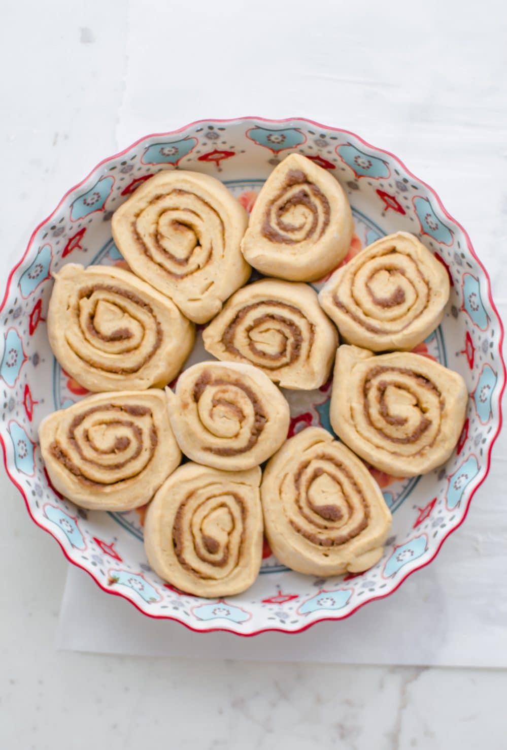 An overhead shot of a pie dish filled with unbaked sweet potato cinnamon rolls. 