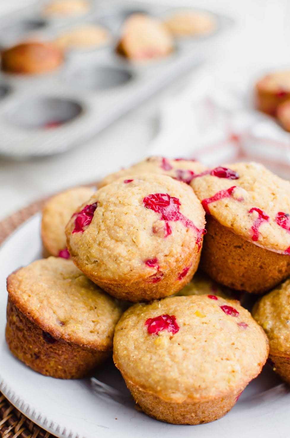 A close up shot of a white plate filled with cranberry cornbread muffins.