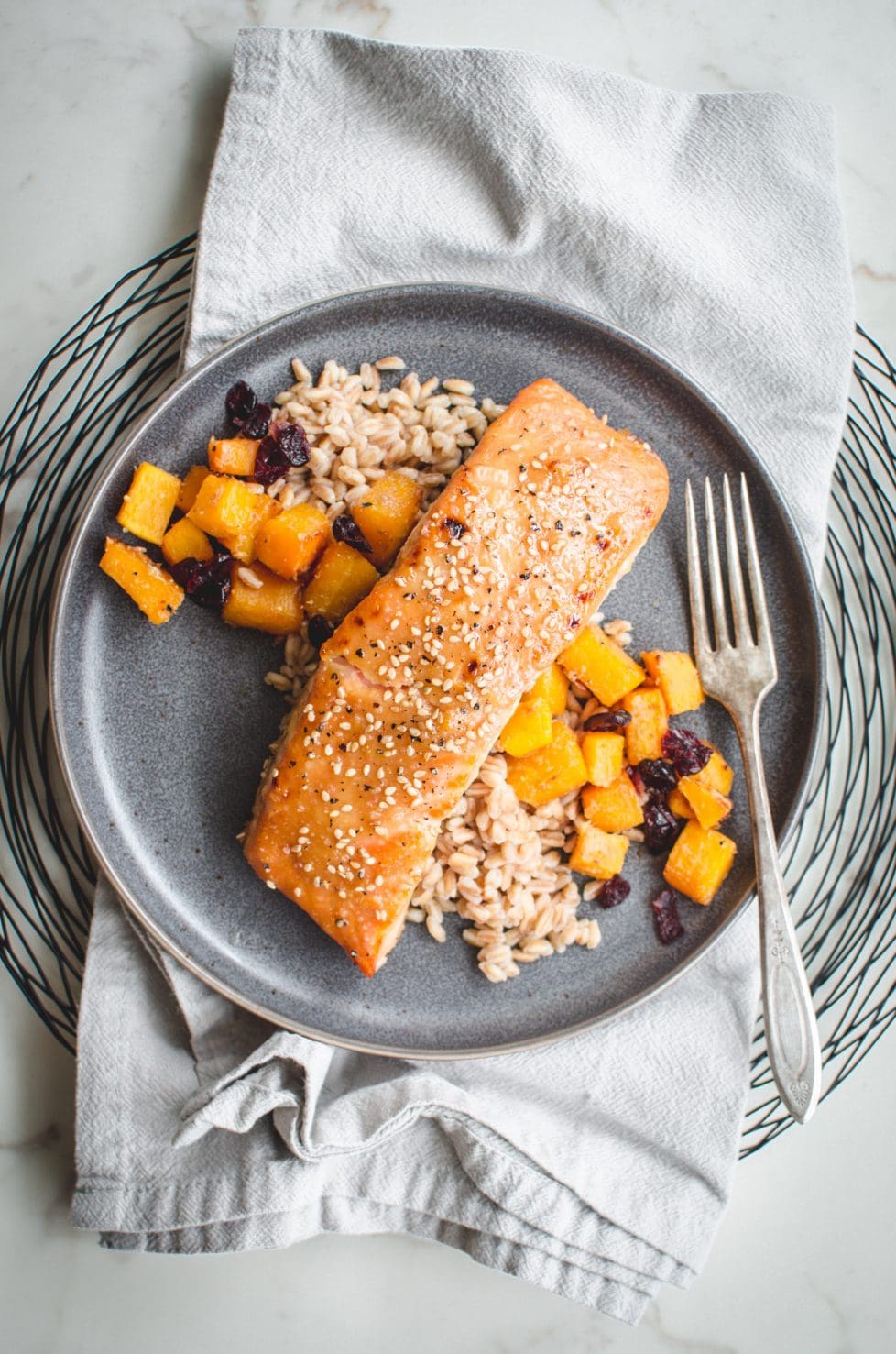 An overhead shot of a gray plate with miso maple roasted salmon, farro, and butternut squash on top.