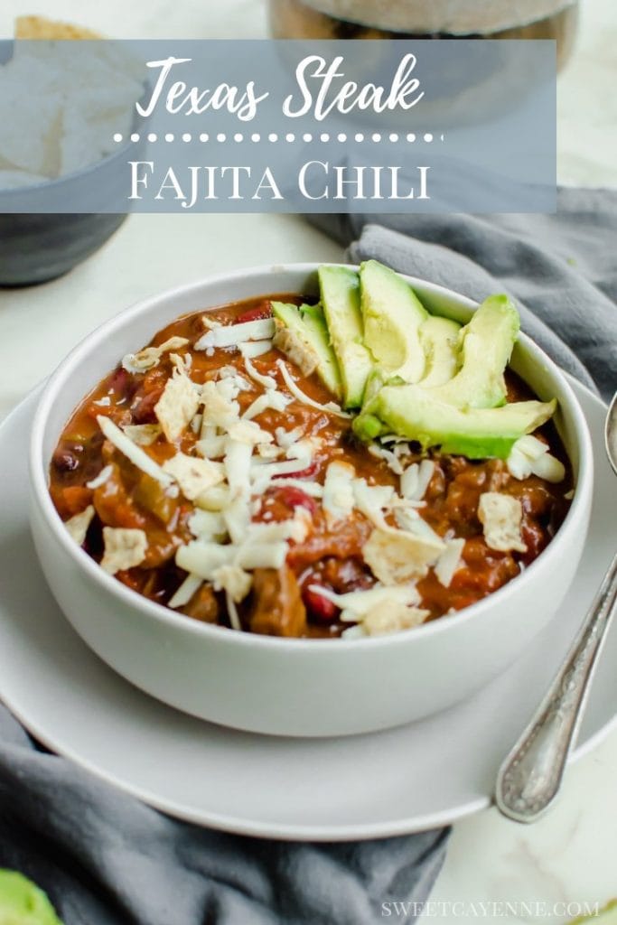 A bowl of chili garnished with avocado slices and shredded cheese.