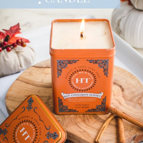 An overhead shot of a candle made in a tea tin sitting on a cutting board against a white background.