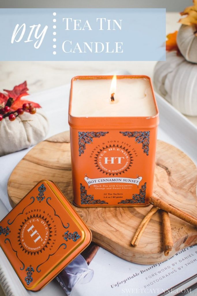 An overhead shot of a candle made in a tea tin sitting on a cutting board against a white background.