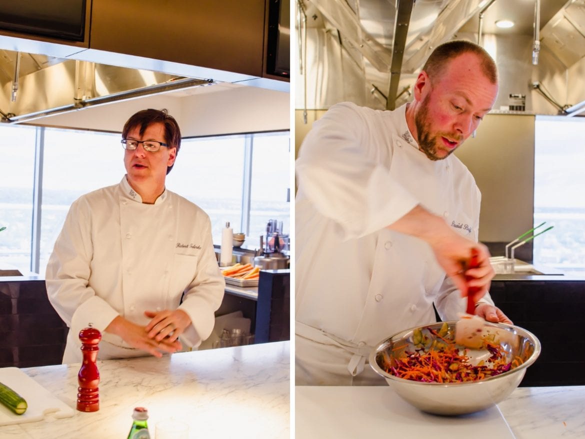 Two chefs preparing food in a demonstration kitchen. 