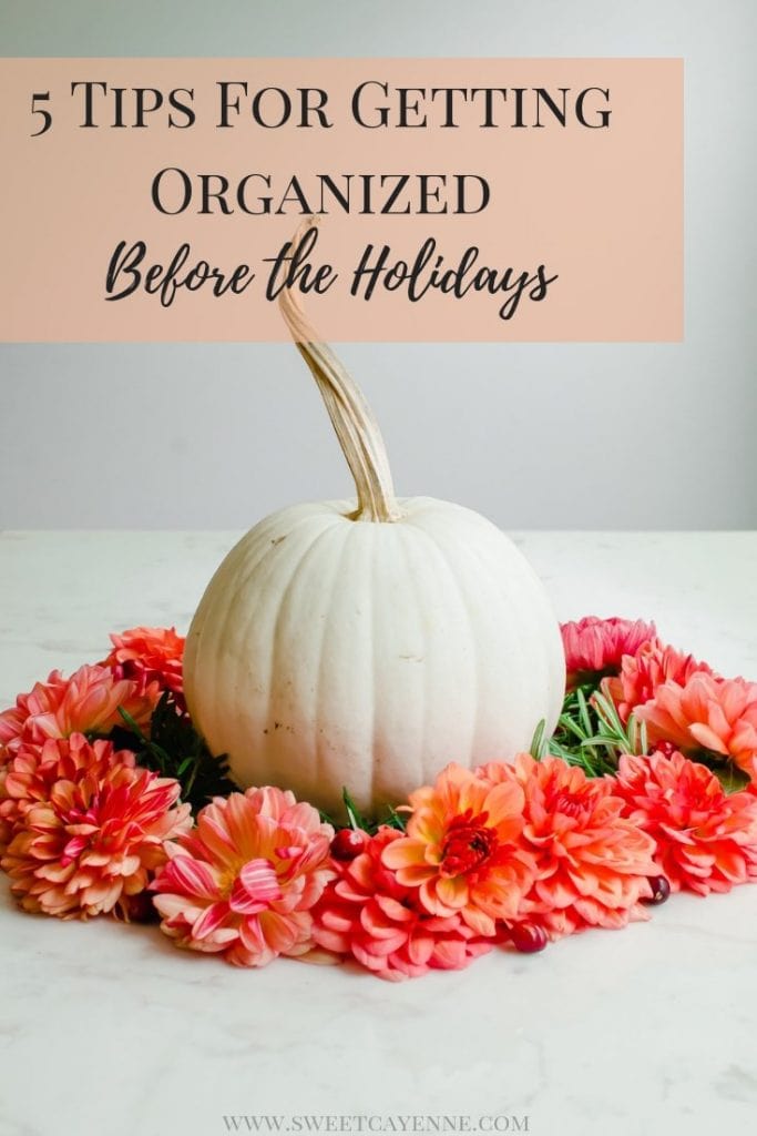 A white pumpkin surrounded by a wreath of coral-colored dahlia flowers.