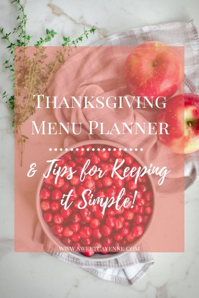 A white bowl of cranberries with two honeycrisp apples and a bunch of fresh thyme on a white counter. 