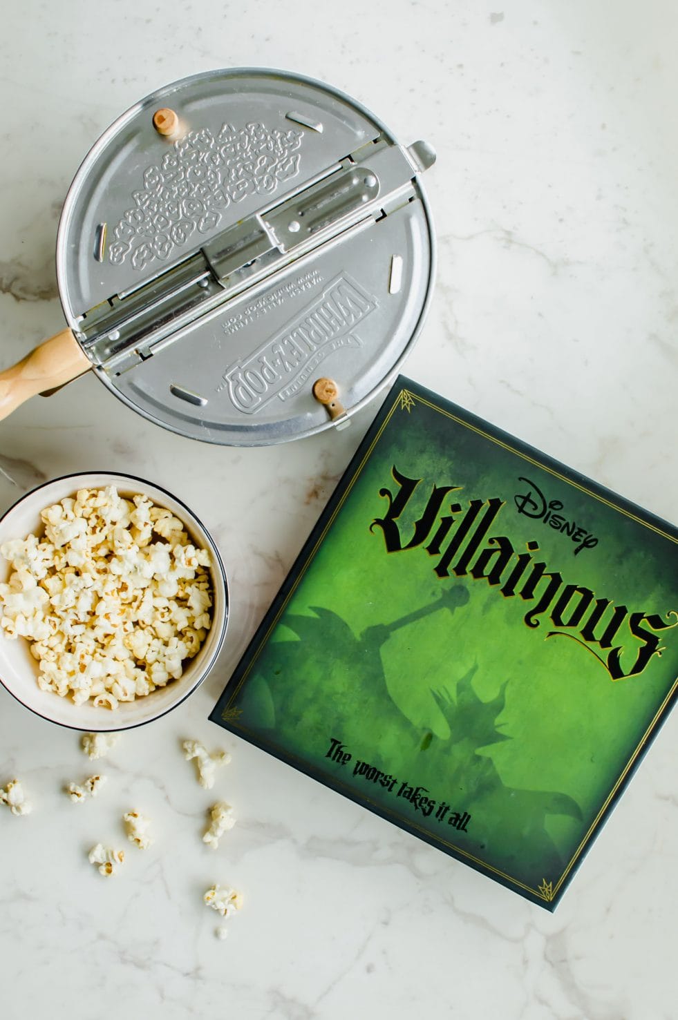 The Disney Villainous game next to a Whirly Pop and bowl of popcorn.