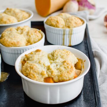 A white ramekin filled with turkey pot pie and drop biscuit topping.