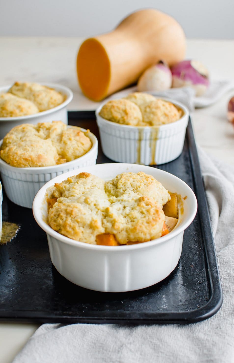 A white ramekin filled with turkey pot pie and drop biscuit topping.