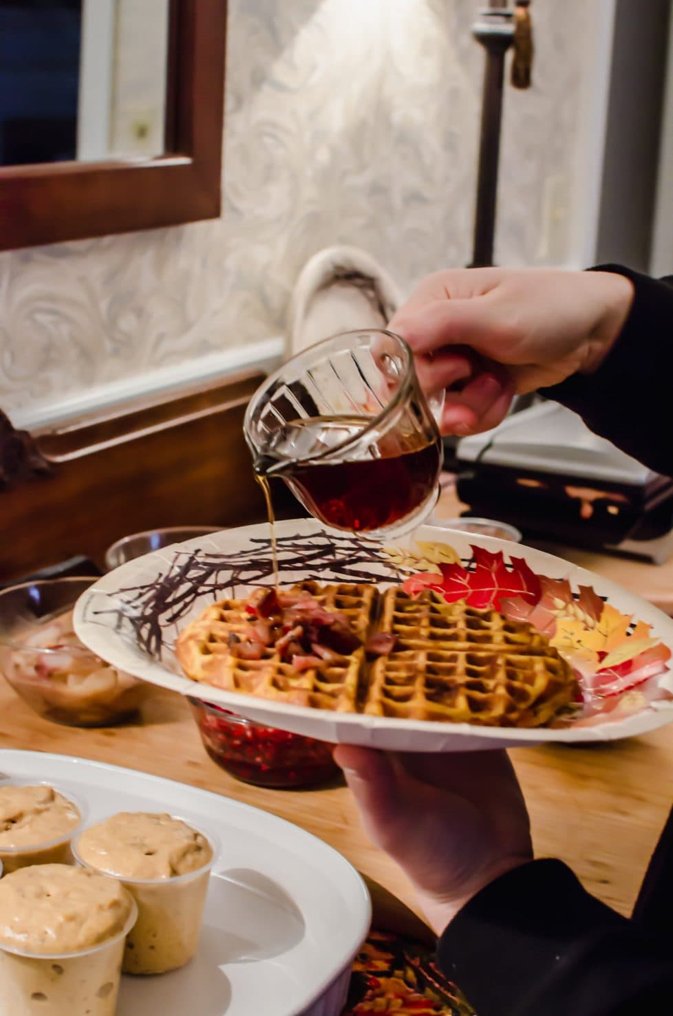 Maple syrup being poured on a pumpkin waffle. 