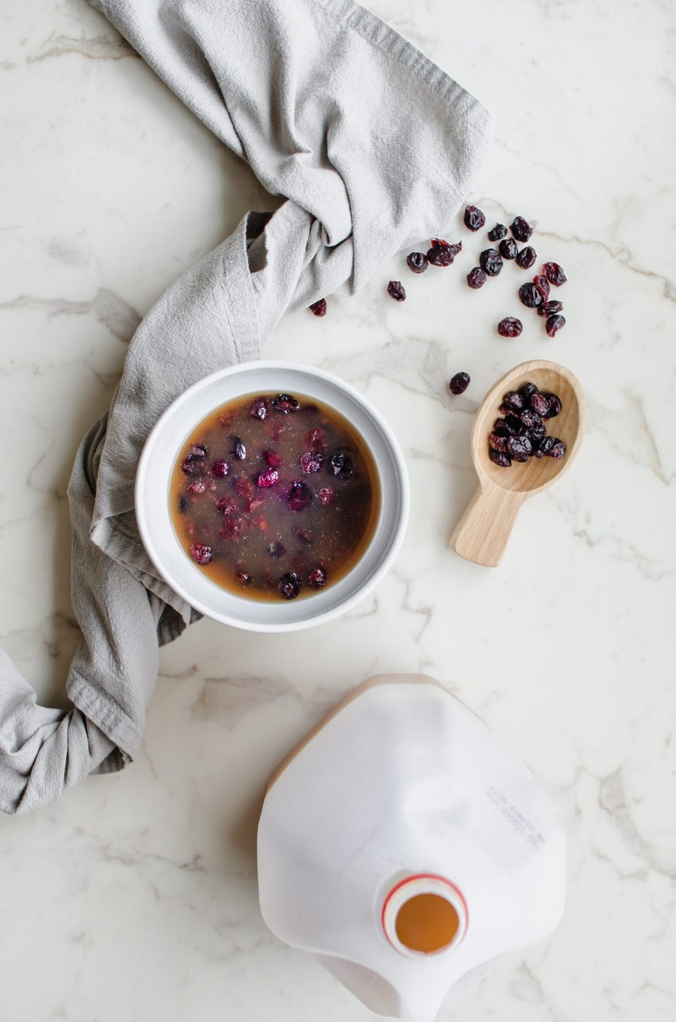 Dried cranberries soaking in apple cider in a white dish.