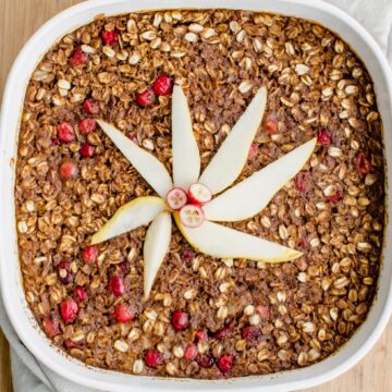 A white casserole dish filled with gingerbread baked oatmeal and topped with pear slices.