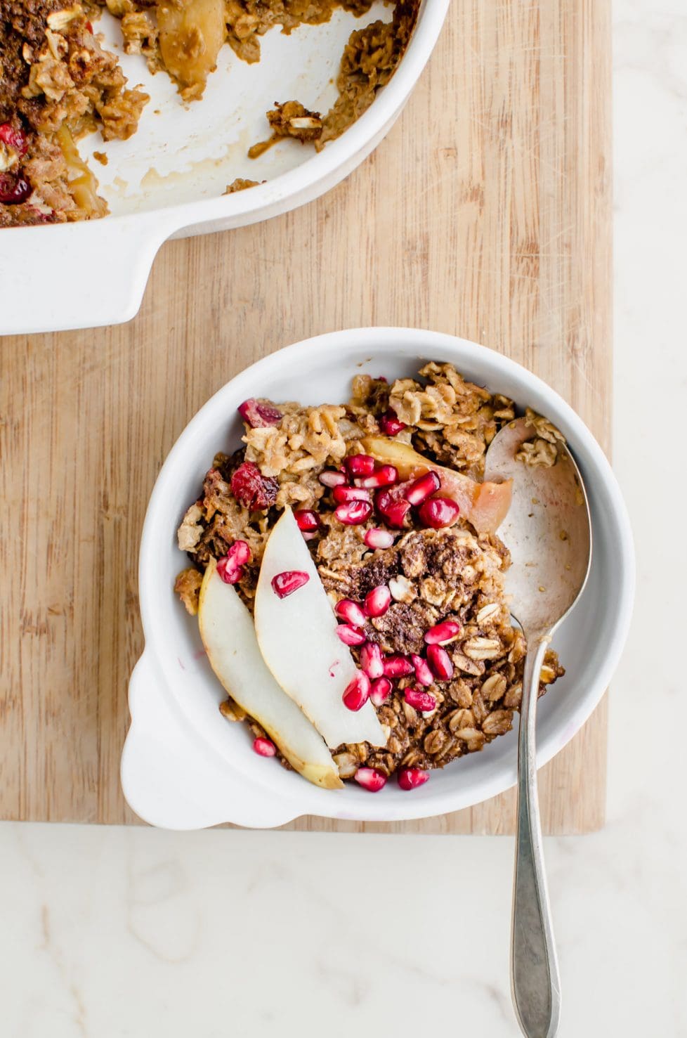 A white dish of gingerbread baked oatmeal on a current board. 