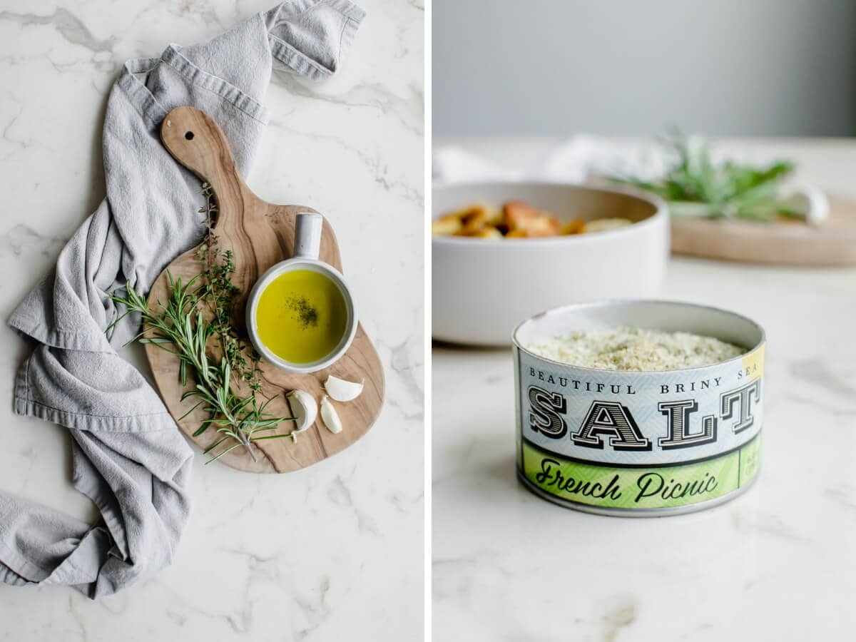 A cutting board with herbs, a bowl of olive oil, and a container of sea salt. 