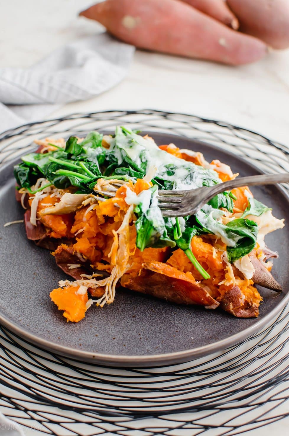 A grey plate with a Buffalo Chicken Stuffed Sweet Potato on top.