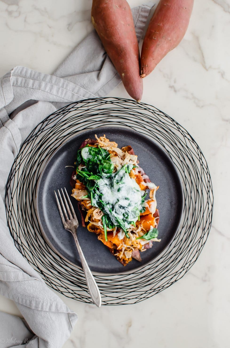 A grey plate with a Buffalo Chicken Stuffed Sweet Potato on top. 