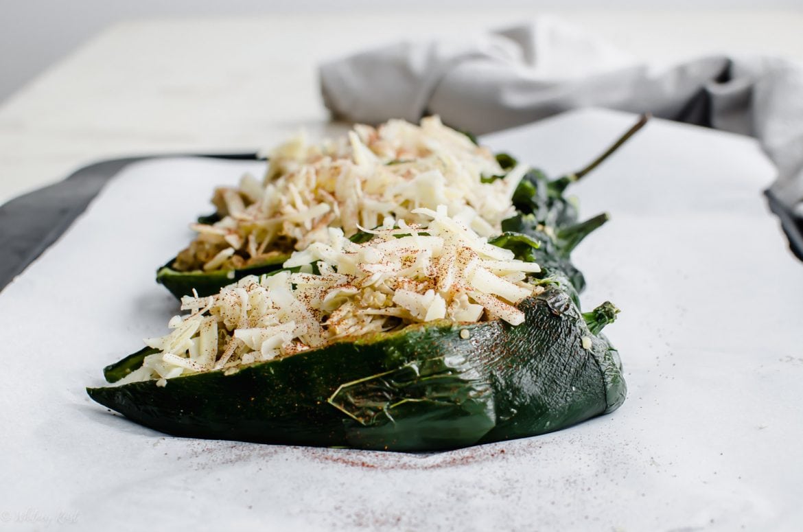 A sheet pan with unbaked stuffed poblano peppers.