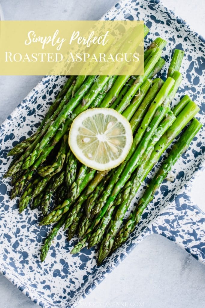 A blue and white tray with roasted asparagus and a lemon slice on top.