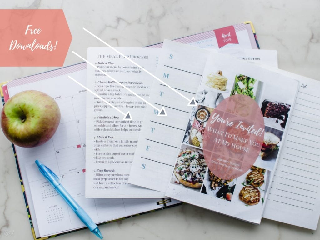 Menu planning sheets with a planner and apple on a white marble counter.