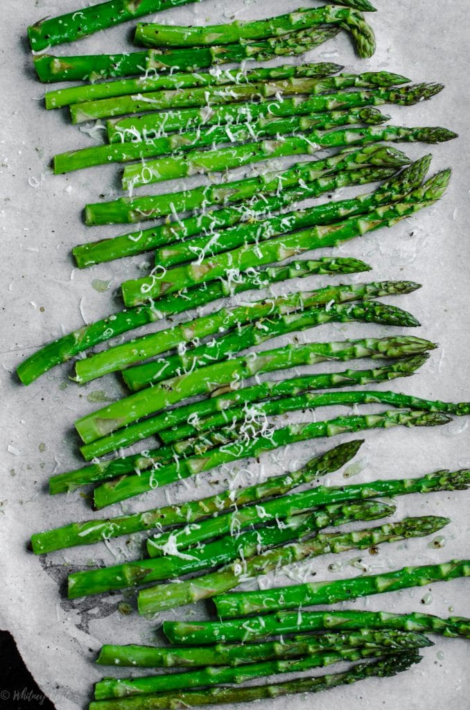 A sheet pan lined with parchment paper and filled with roasted asparagus.