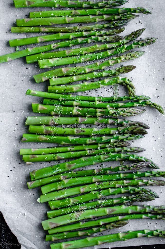 A sheet pan lined with parchment paper and filled with roasted asparagus.