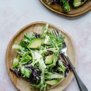 An overhead shot of wooden plates with springtime everyday salad on top.