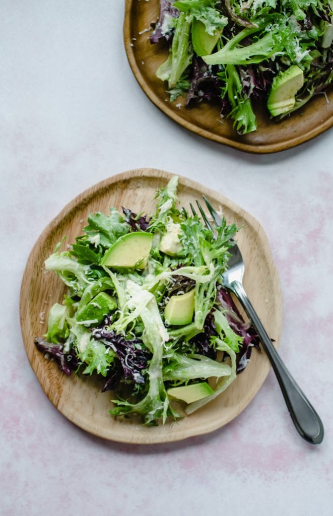 An overhead shot of wooden plates with springtime everyday salad on top.