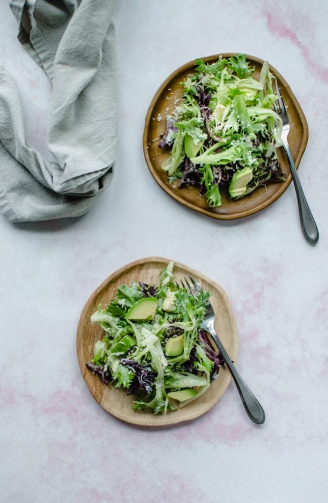 An overhead shot of wooden plates with springtime everyday salad on top.