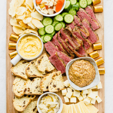 A St. Patrick's day themed snack board with corned beef, sauerkraut, soda bread, and other charcuterie items.