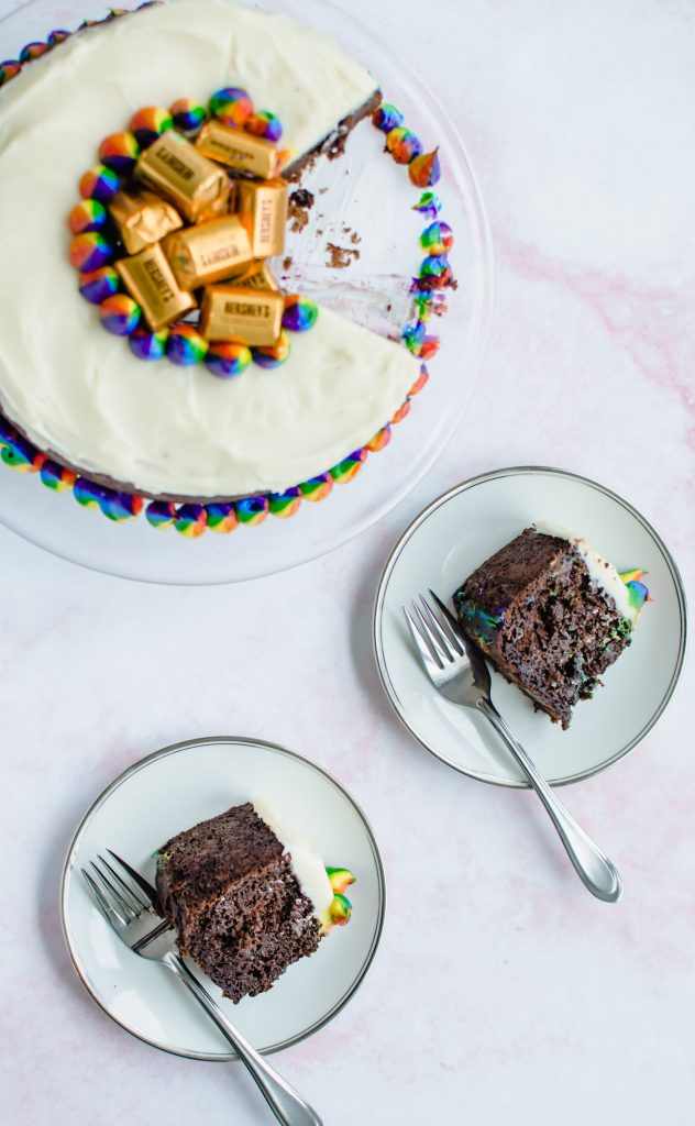 A chocolate stout cake on a glass cake stand with plates of cake on the side.