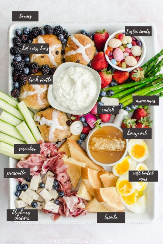 A white rectangle platter filled with items for an Easter brunch grazing board against a pink marble background.