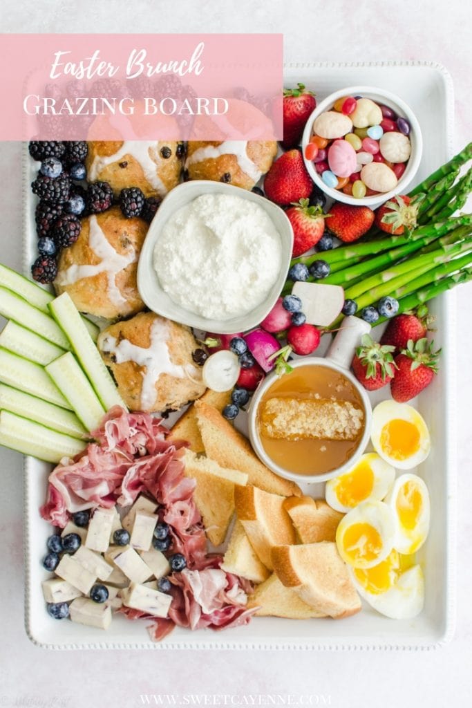 A white rectangle platter filled with items for an Easter brunch grazing board against a pink marble background.