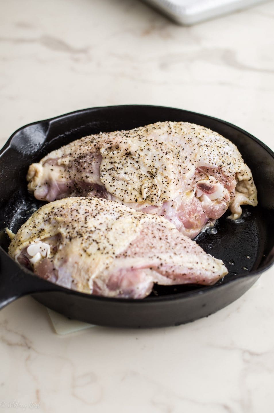 Seasoned chicken breasts in a cast iron skillet. 