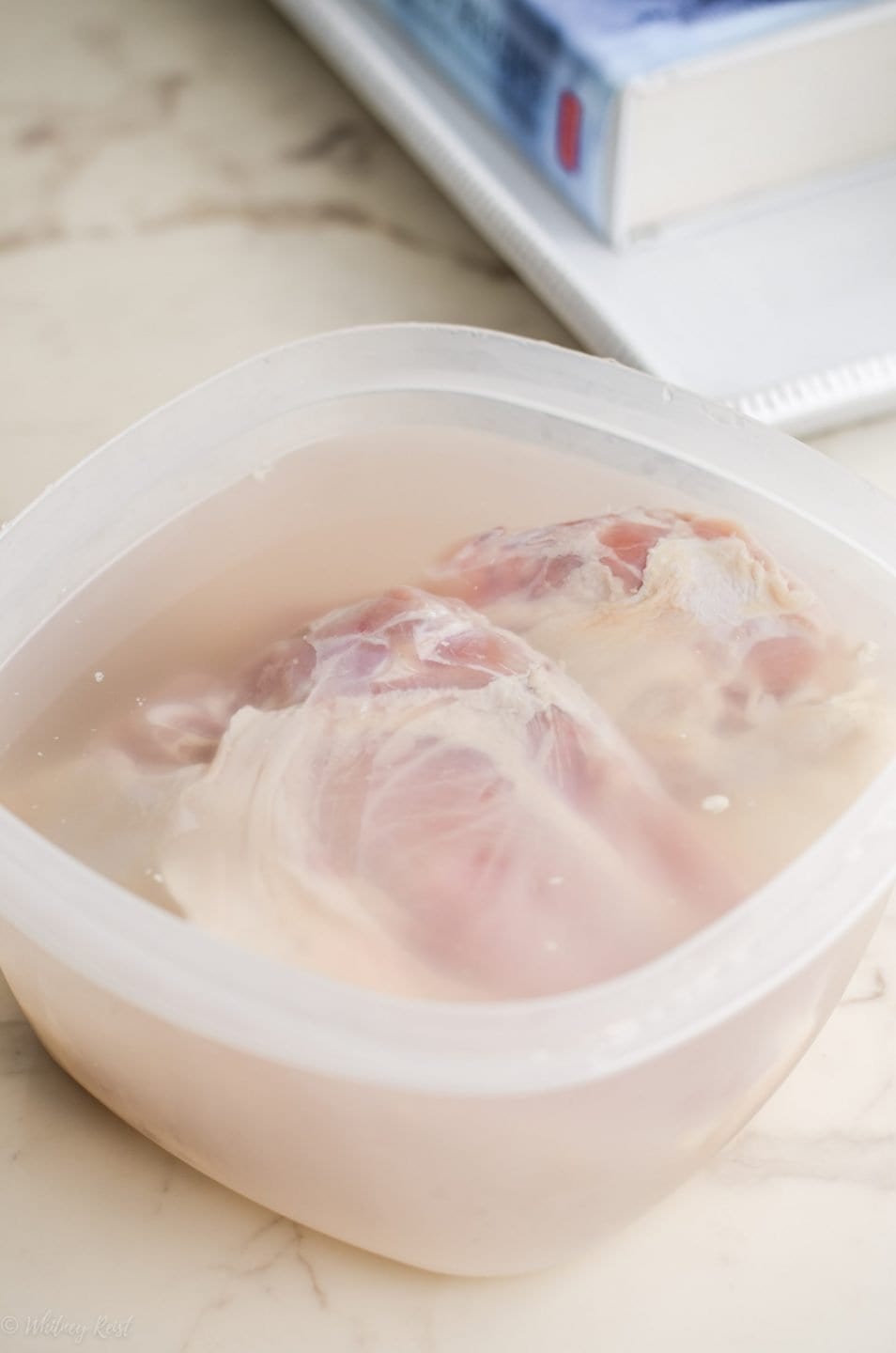 Chicken breasts brining in a tupperware with salt water solution. 