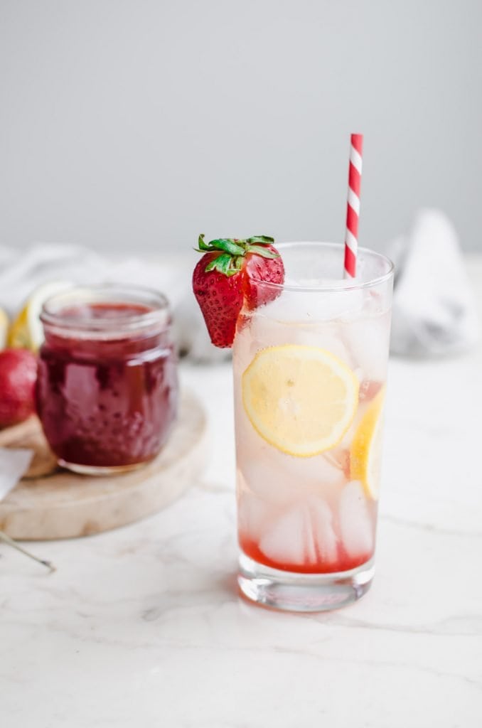 A sparkling water beverage with a strawberry and lemons in it.