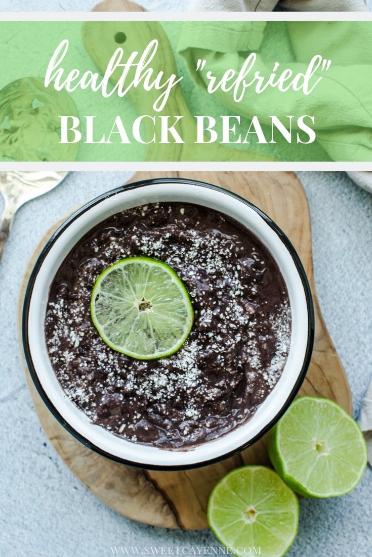 An overhead shot of refried black beans in a white bowl topped with cotijacheese and a lime slice with Pinterest text overlay.