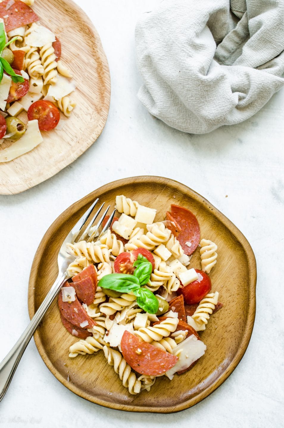 Two wooden plates filled with pizza pasta salad and forks on the side against a white background.