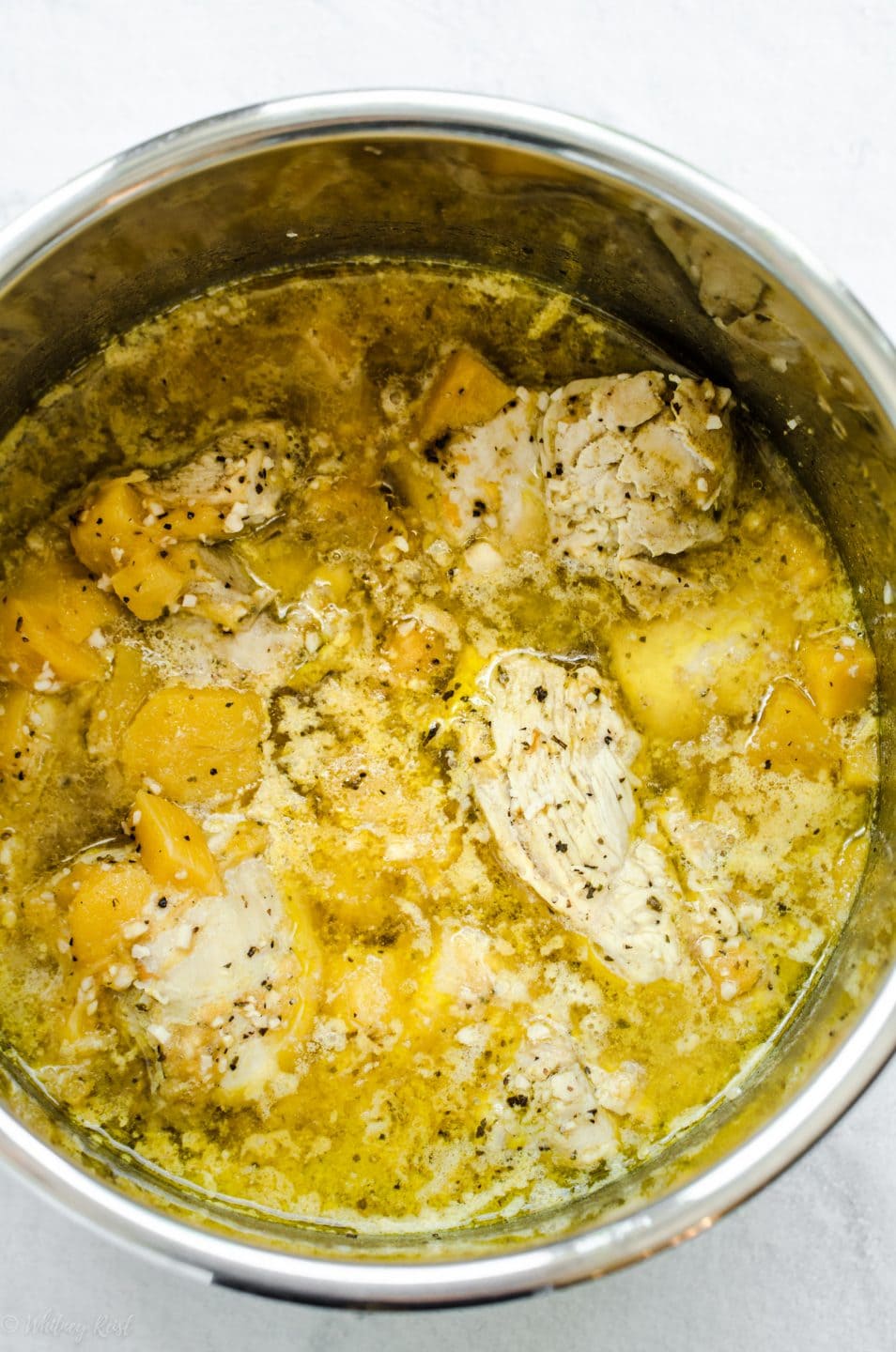 An overhead shot of the inside of an Instant Pot filled with chicken, mangoes, and mojo sauce.