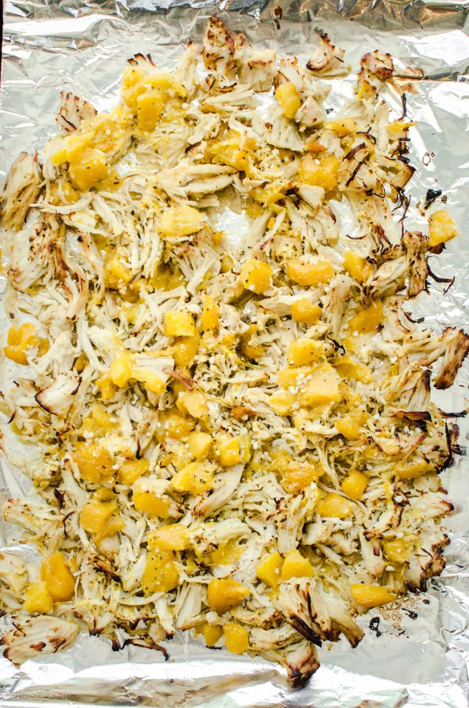 A sheet pan with shredded Mango Mojo Chicken crisped under the broiler.