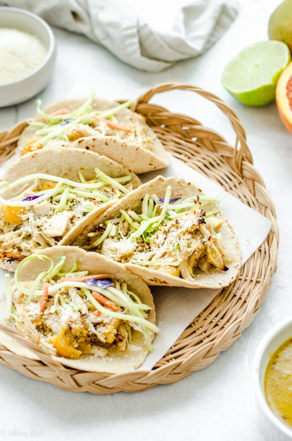 A side shot of a wicker charger filled with Mango Mojo Chicken Tacos.