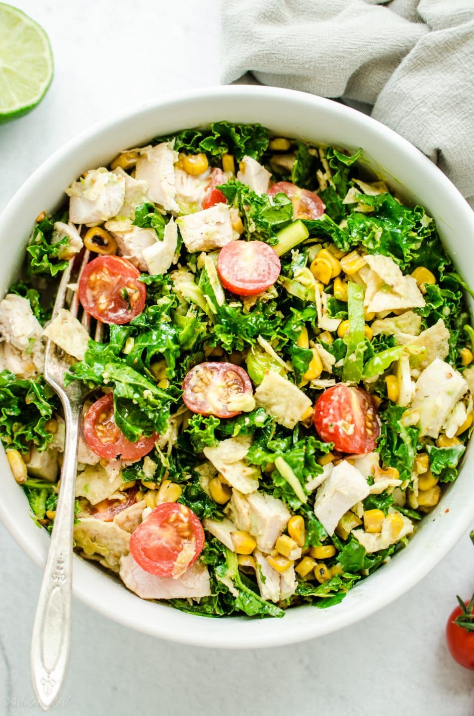 An overhead shot of a white bowl filled with chopped Mexican kale salad.