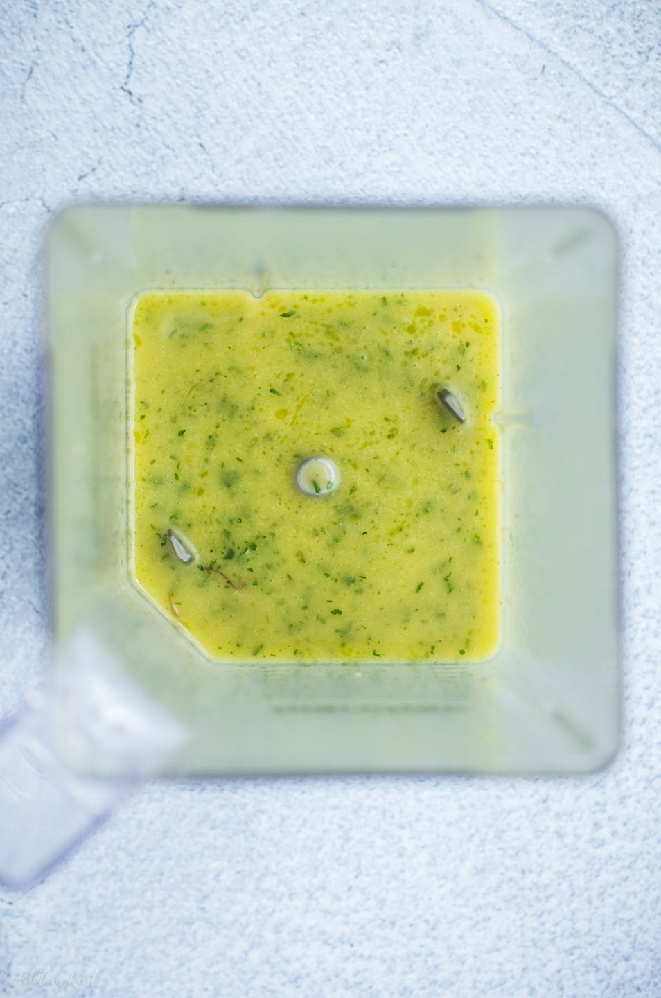 An inside shot of a blender with fresh mint vinaigrette. 