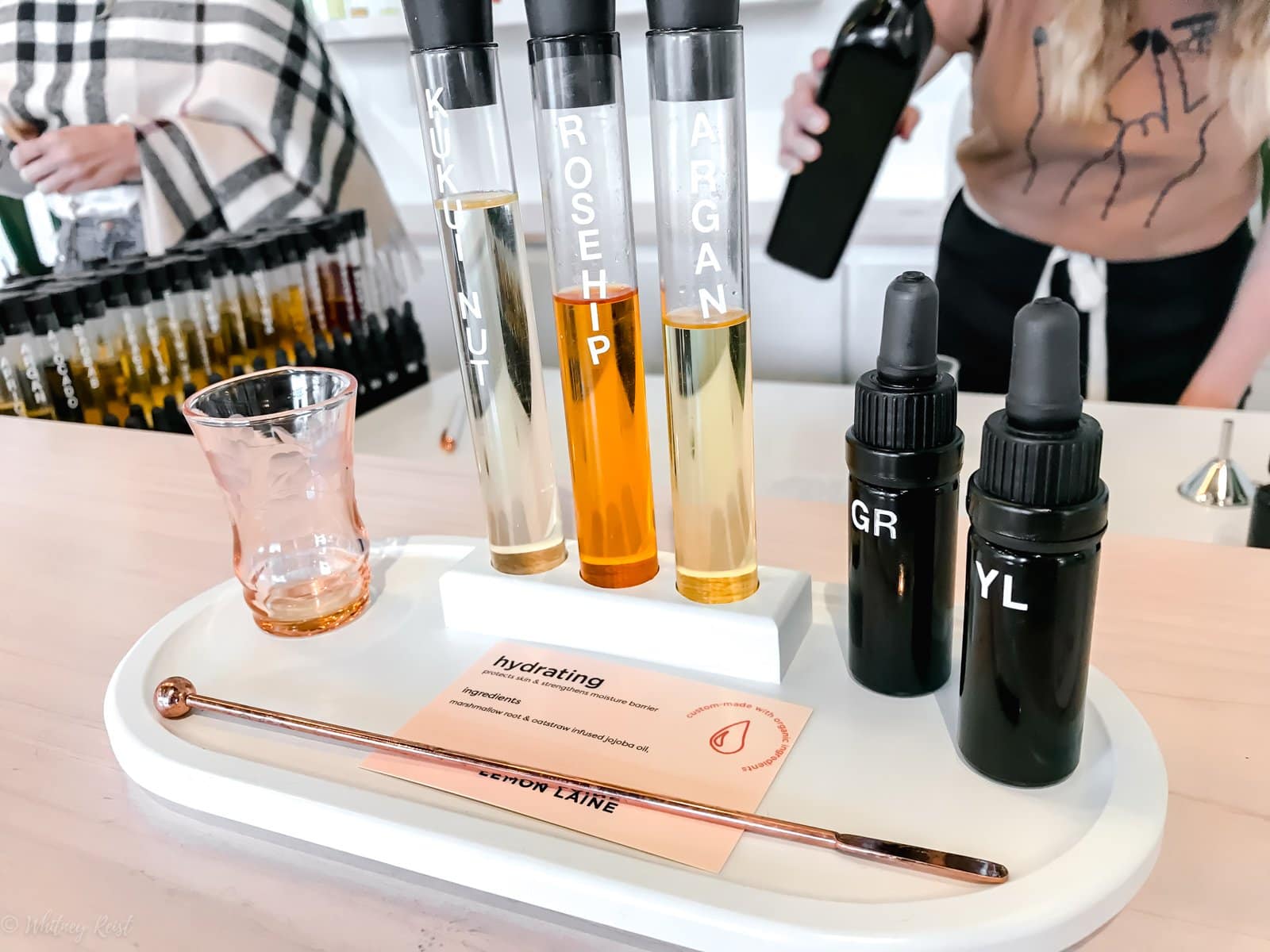 A tray with serums and ingredients and a mixer cup for making a custom facial oil.