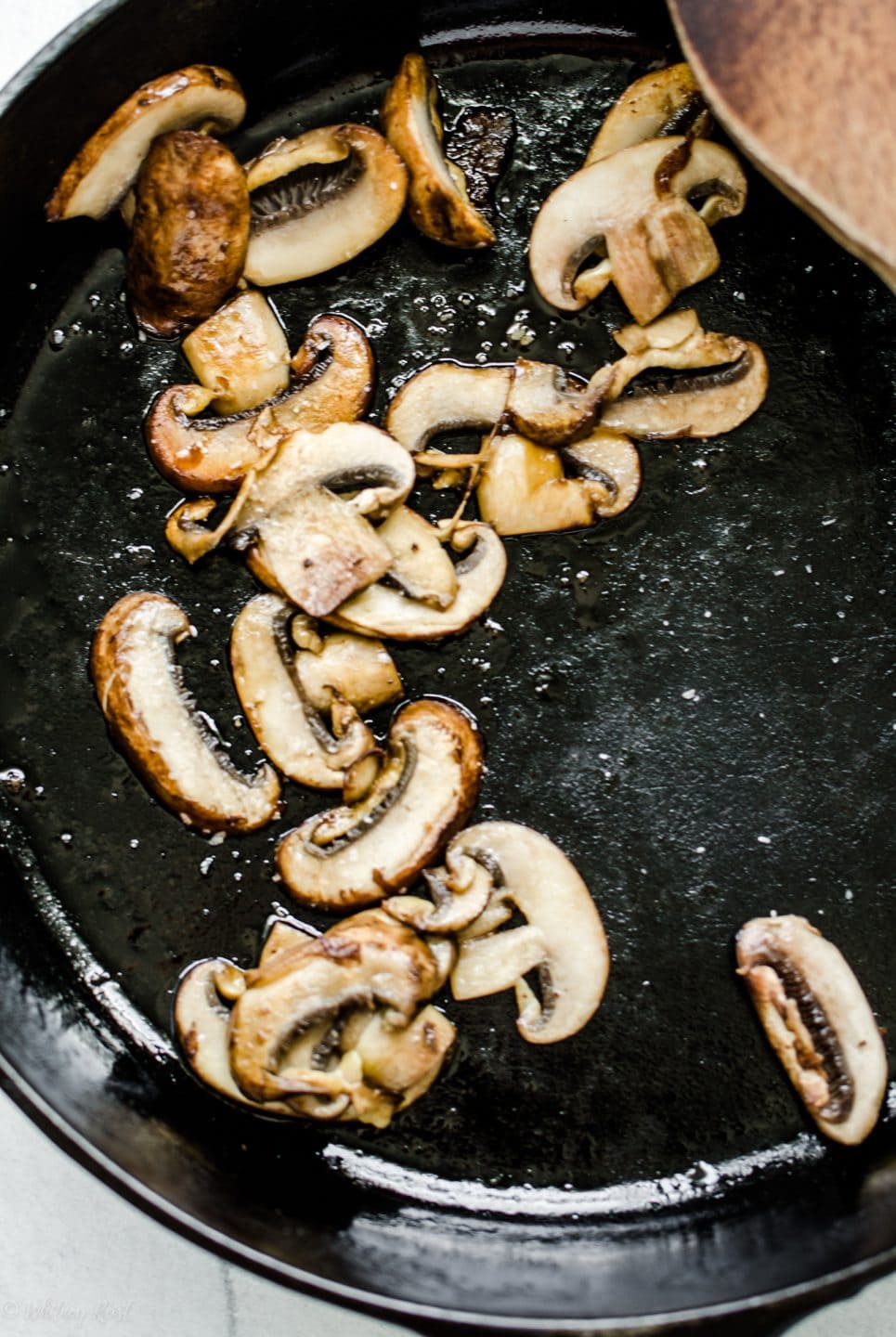 Sliced mushrooms being browned in a cast iron skillet. 